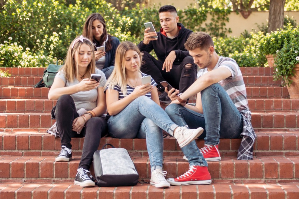 Jóvenes españoles en un aula con pantallas y tecnología de IA en uso.