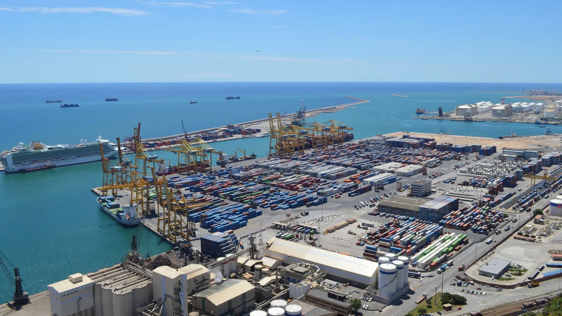 Barcos españoles en puerto internacional con banderas y carga en movimiento