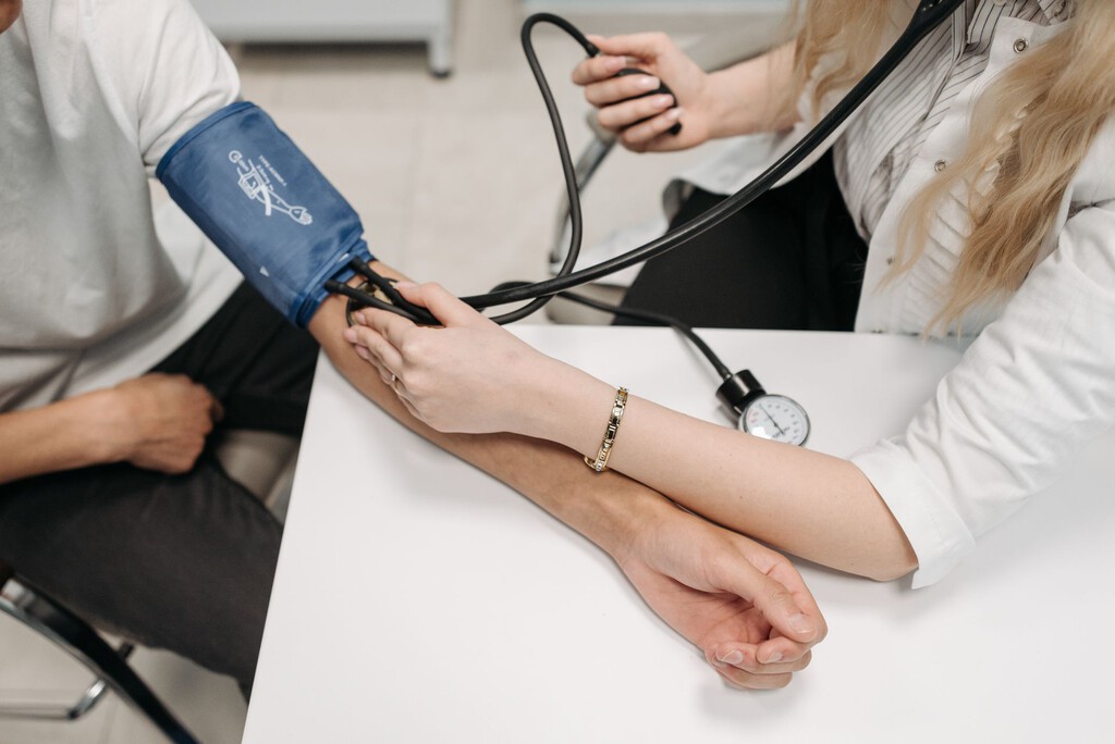 Profesional médico midiendo la presión arterial con dispositivo automatizado en consulta clínica.